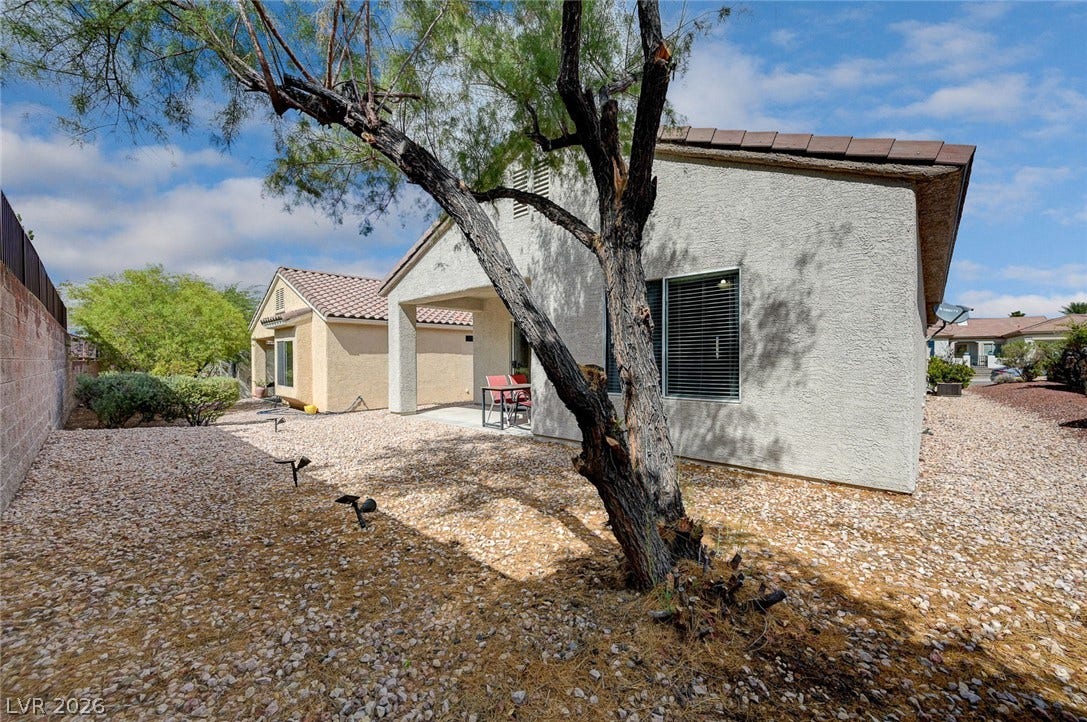 2851 Sapphire Desert Drive, Henderson, NV 89052 Low-maintenance gravel landscaping and mature trees frame the rear exterior of this stucco home.