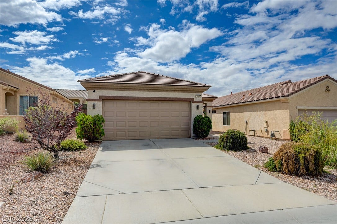 2851 Sapphire Desert Drive, Henderson, NV 89052 A wide concrete driveway leads directly to the attached two-car garage of this stucco home.