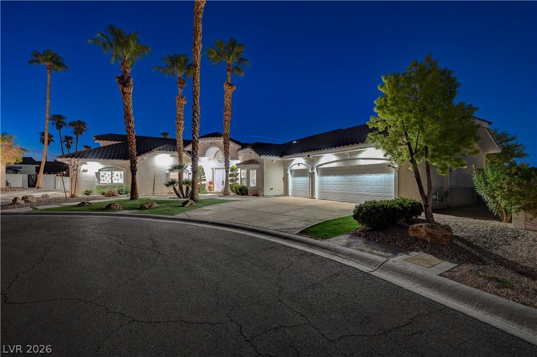 2000 Alexa Breanne Court, Las Vegas, NV 89117 Dramatic night lighting accentuates the elegant stucco facade and soaring palm trees of this desert home.