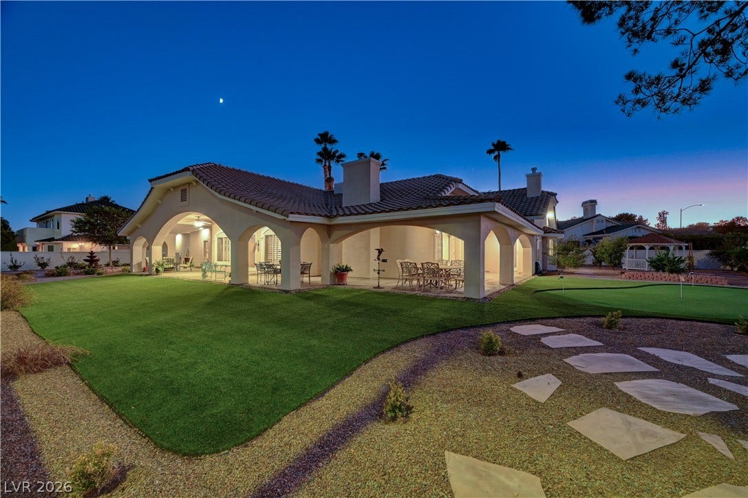 2000 Alexa Breanne Court, Las Vegas, NV 89117 Arched covered patios overlook a sprawling manicured lawn under a twilight sky.