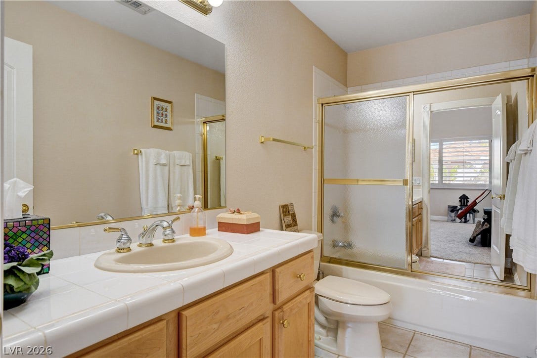 2000 Alexa Breanne Court, Las Vegas, NV 89117 Tiled countertops and a wood vanity define this classic full bathroom setup.
