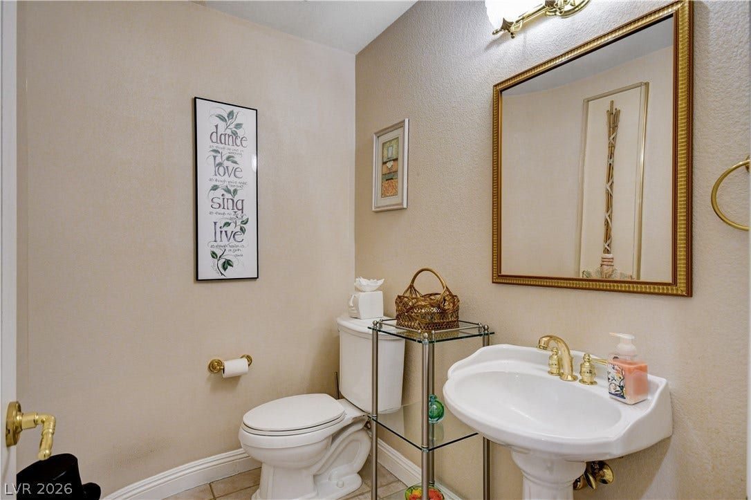 2000 Alexa Breanne Court, Las Vegas, NV 89117 A classic pedestal sink paired with golden fixtures anchors this neutral half bathroom.