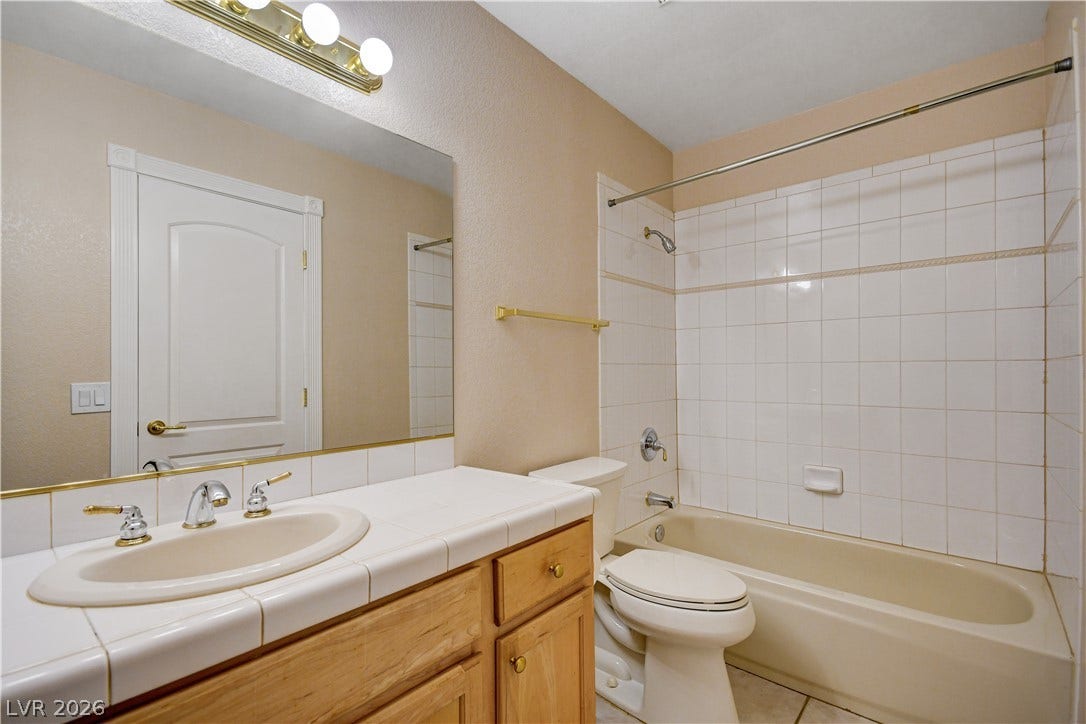2000 Alexa Breanne Court, Las Vegas, NV 89117 Tiled vanity countertops and a matching tub surround define this classic full bathroom setup.