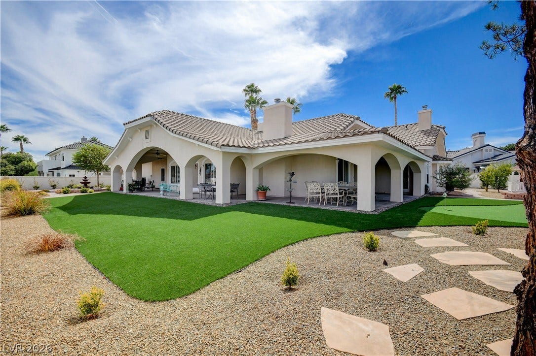 2000 Alexa Breanne Court, Las Vegas, NV 89117 Elegant arched loggias frame a beautifully landscaped backyard with a manicured lawn and tile roof.