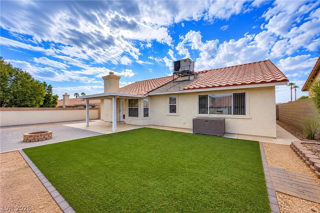 4722 Casa Bonita Drive, North Las Vegas, NV 89032 An inviting backyard features a tiled roof, covered patio, fire pit, and low-maintenance green lawn.