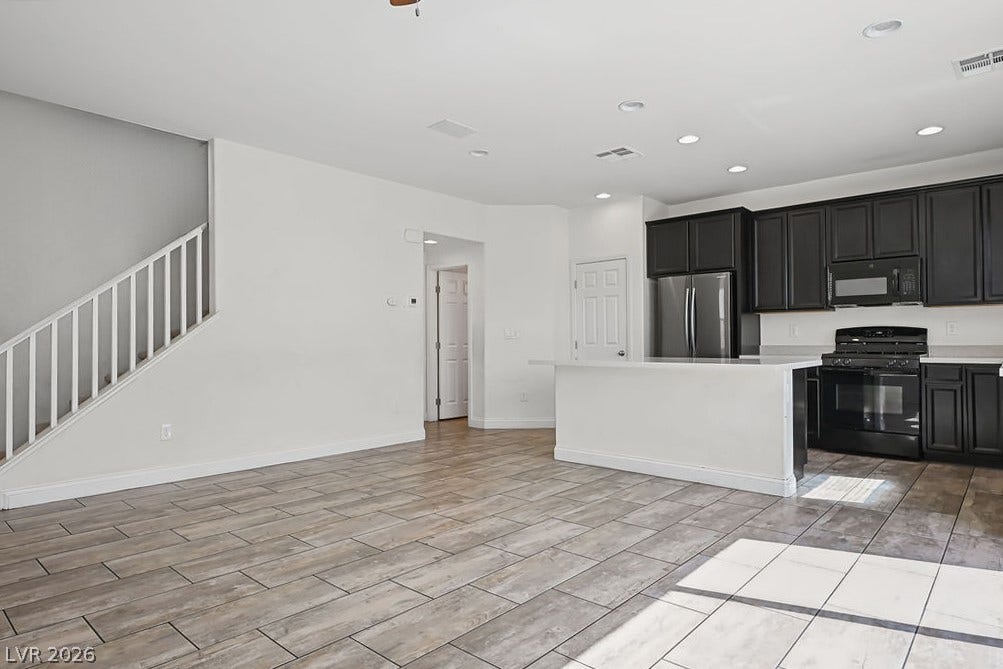 Wood-look tile floors run through this open-concept layout connecting the kitchen and living areas.