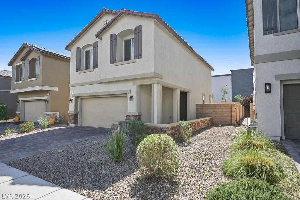 Desert landscaping and a paved driveway complement this two-story stucco home with a private entrance.