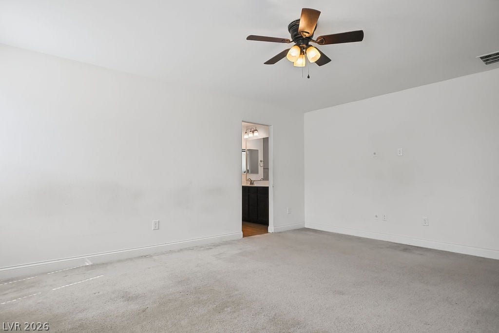 An open doorway connects this carpeted bedroom space directly to an en suite bathroom.