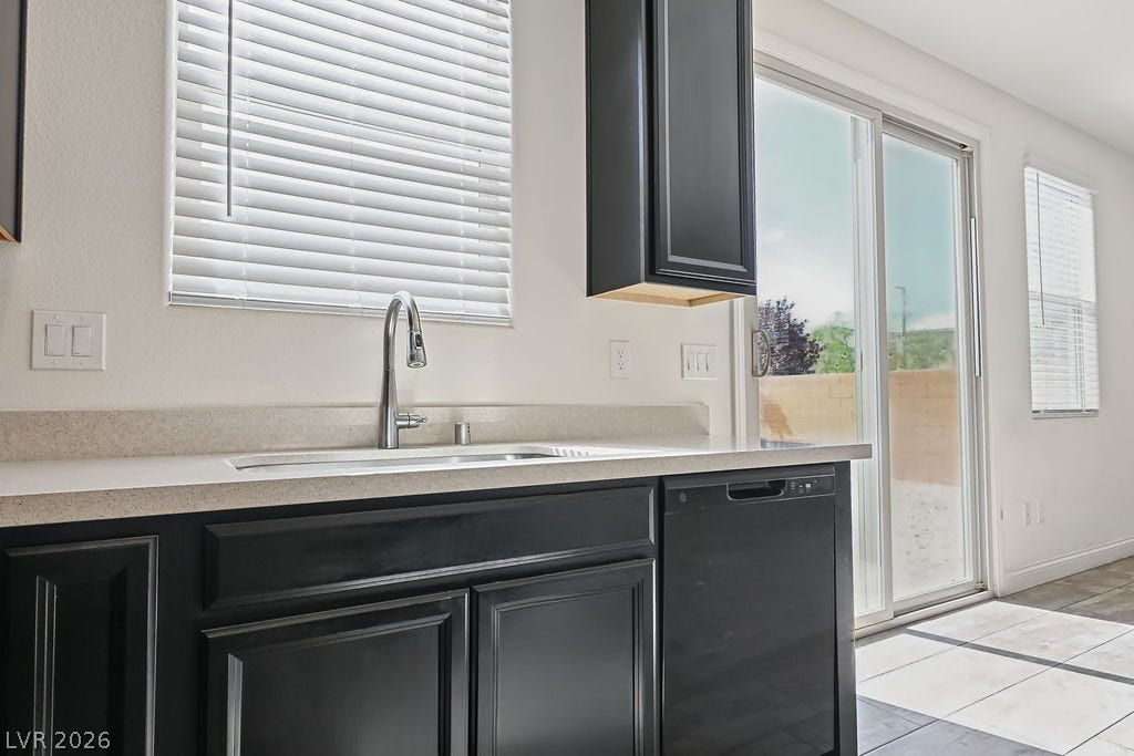 A modern kitchen sink area sits adjacent to sliding glass doors opening to the patio.
