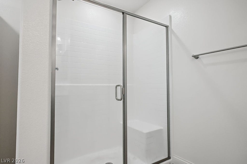 A glass-enclosed walk-in shower features classic subway tiling and a built-in bench seat.
