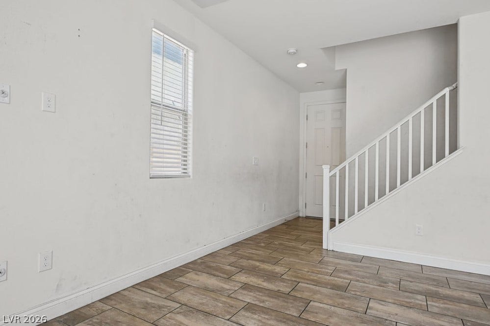 Wood-look tile flooring and a classic white staircase create a welcoming entry space.