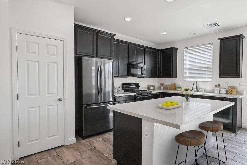 Dark cabinetry beautifully contrasts with light stone countertops surrounding a spacious central island.