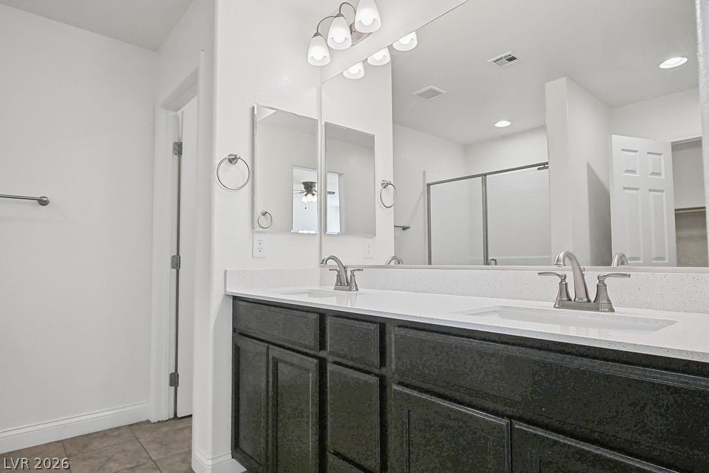 A spacious double vanity features clean stone countertops and dark cabinetry beneath a wide mirror.