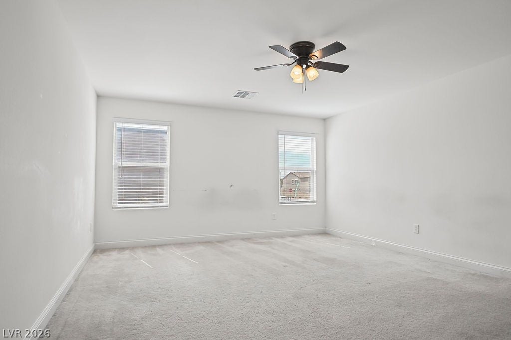 Dual windows fill the carpeted room with natural light.