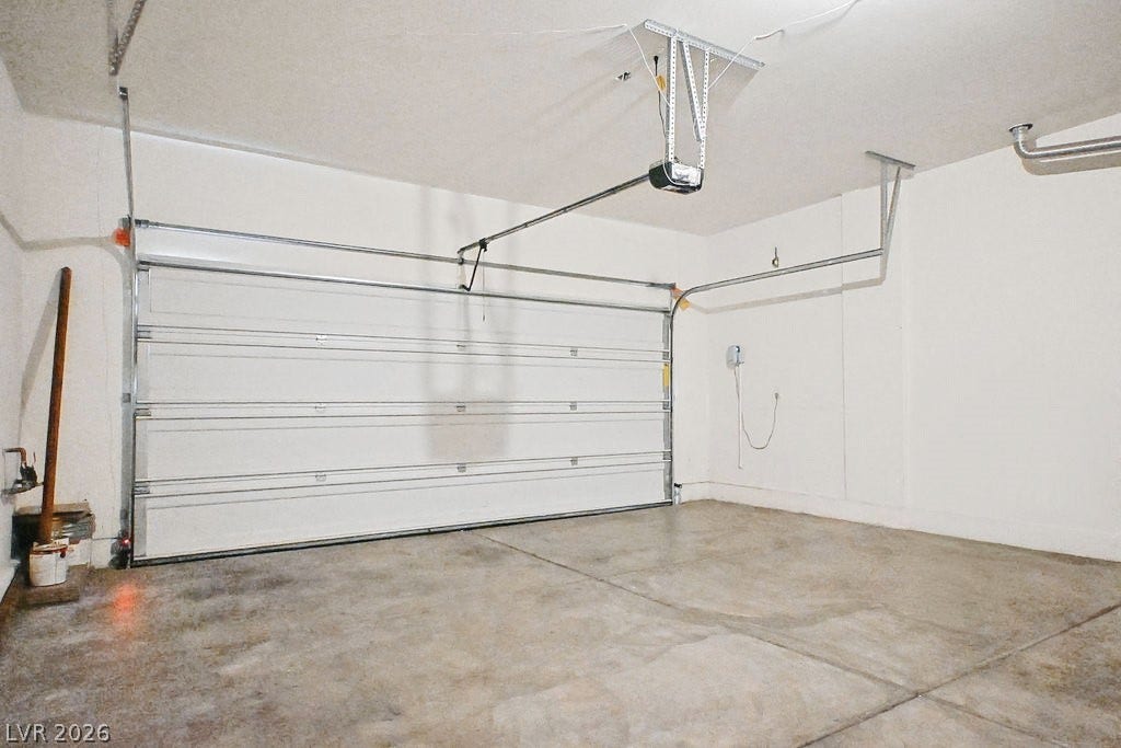 An accommodating garage features solid concrete flooring and an automatic door opener.