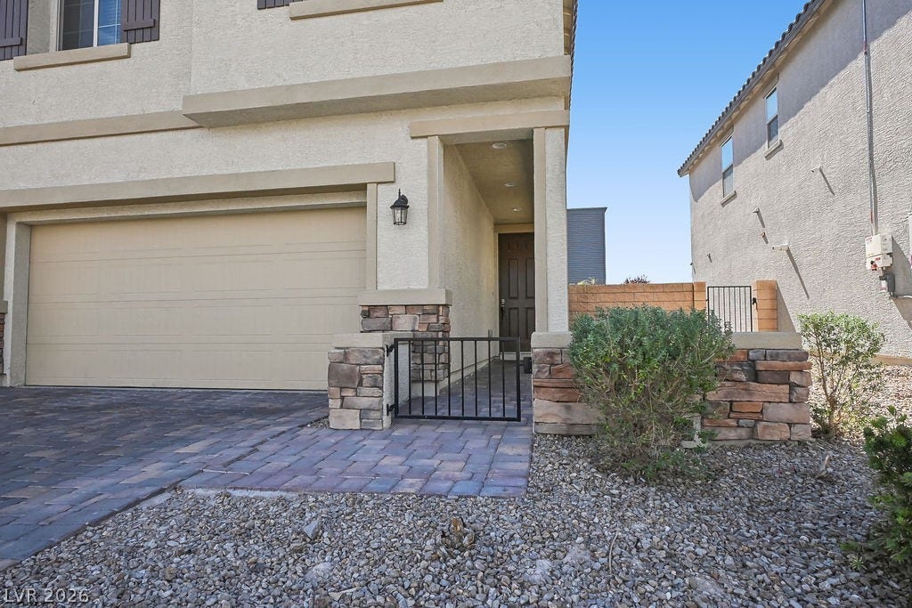 A stone-accented entryway and paver driveway frame the front of this modern multi-level residence.