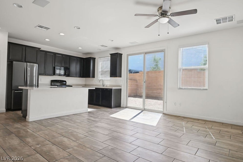 Plank tile flooring runs through an open kitchen and living area featuring sliding glass doors.