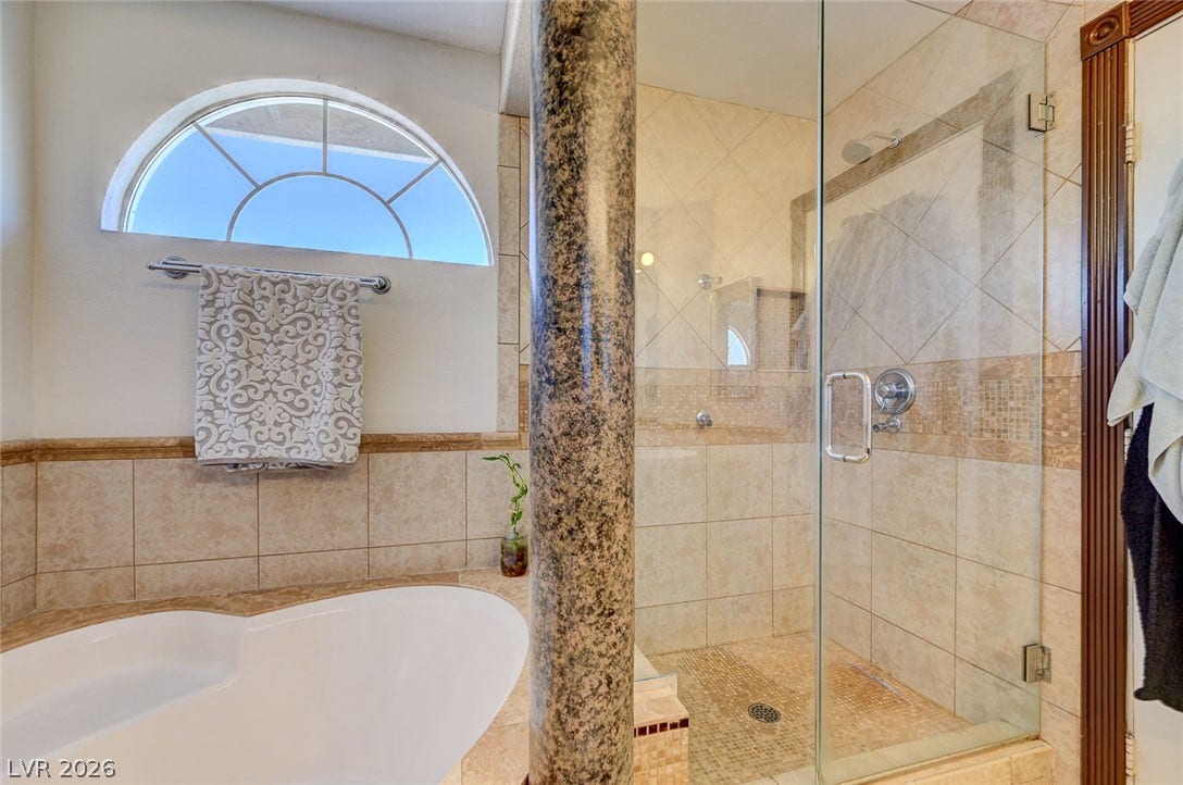 2722 Aspen Wood Avenue, Henderson, NV 89074 An arched window and textured stone pillar accent this tiled bath with walk-in shower.