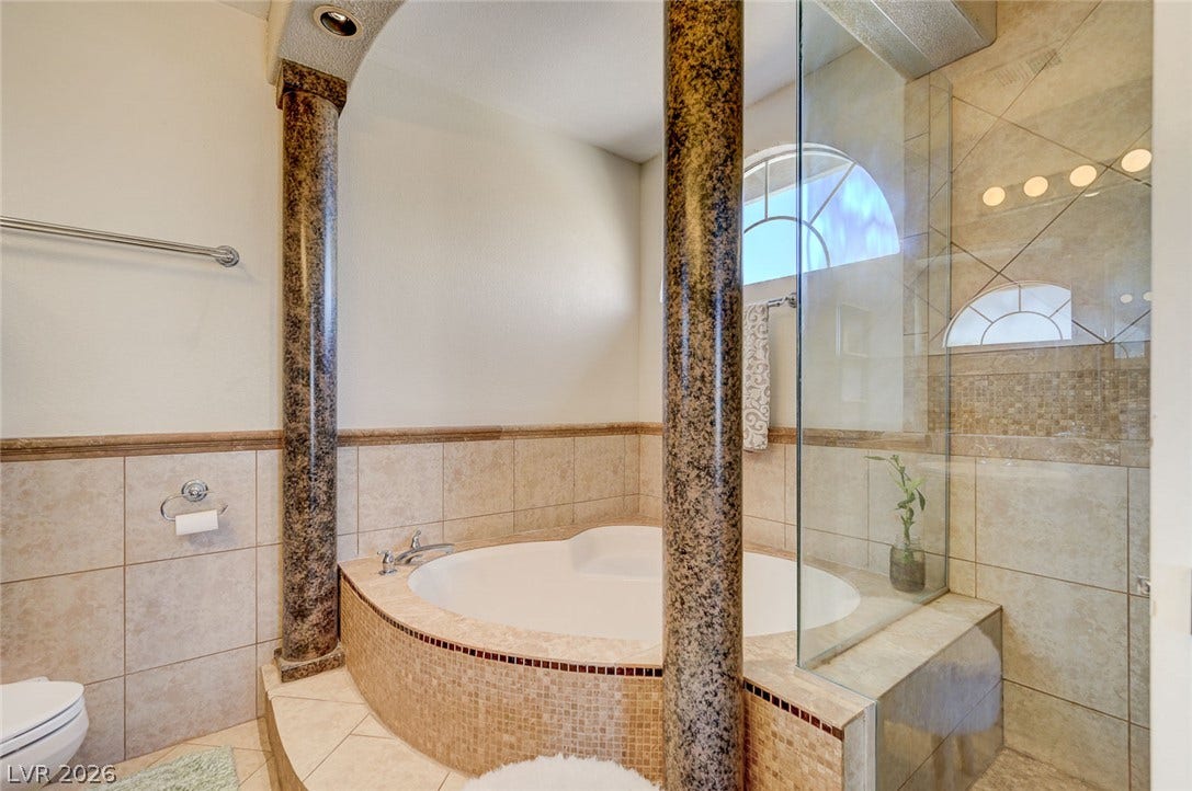 2722 Aspen Wood Avenue, Henderson, NV 89074 Classical stone columns flank a deep soaking tub surrounded by tiled walls.