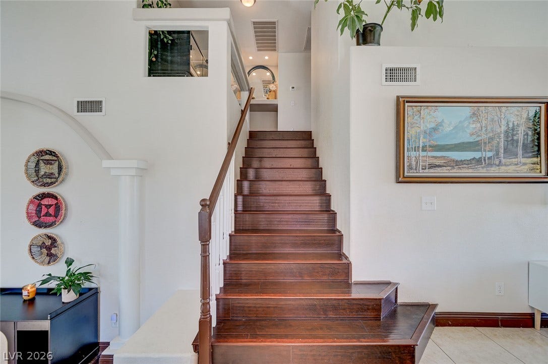 2722 Aspen Wood Avenue, Henderson, NV 89074 Rich wood stairs rise elegantly alongside a classic column detail in this light-filled entryway.