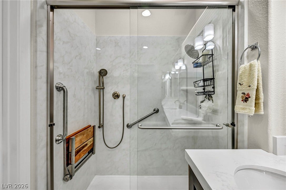 10020 Villa Ridge Drive, Las Vegas, NV 89134 Marble patterned walls highlight this modern walk-in shower with sliding glass doors.