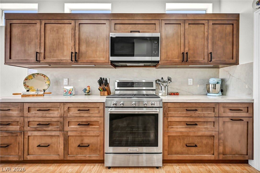 10020 Villa Ridge Drive, Las Vegas, NV 89134 Warm wood cabinetry and solid stone countertops flank a modern stainless steel range.