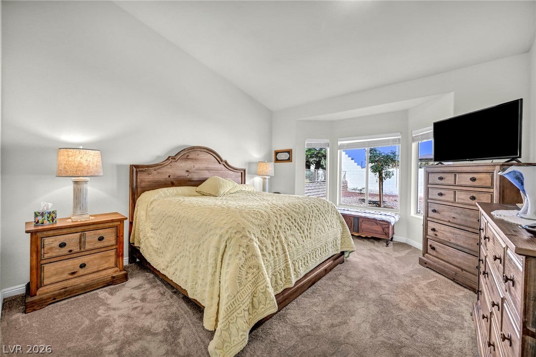 10020 Villa Ridge Drive, Las Vegas, NV 89134 Soft carpeting pairs with a vaulted ceiling and a bay window in this relaxed bedroom.