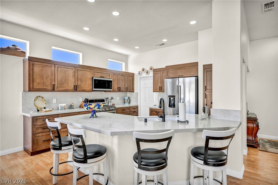 10020 Villa Ridge Drive, Las Vegas, NV 89134 Rich wood cabinetry contrasts beautifully with stone counters in this open-concept kitchen.