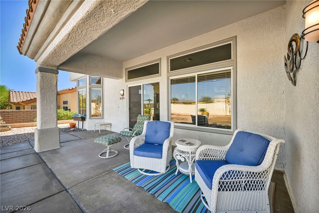 10020 Villa Ridge Drive, Las Vegas, NV 89134 Shaded concrete patio features stucco columns, tiled rooflines, and sliding glass doors.