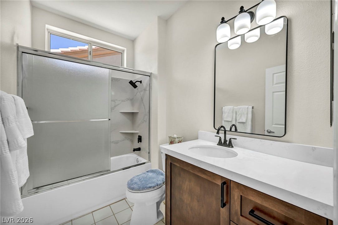 10020 Villa Ridge Drive, Las Vegas, NV 89134 Elegant stone countertops and a modern vanity highlight this refined bathroom design.