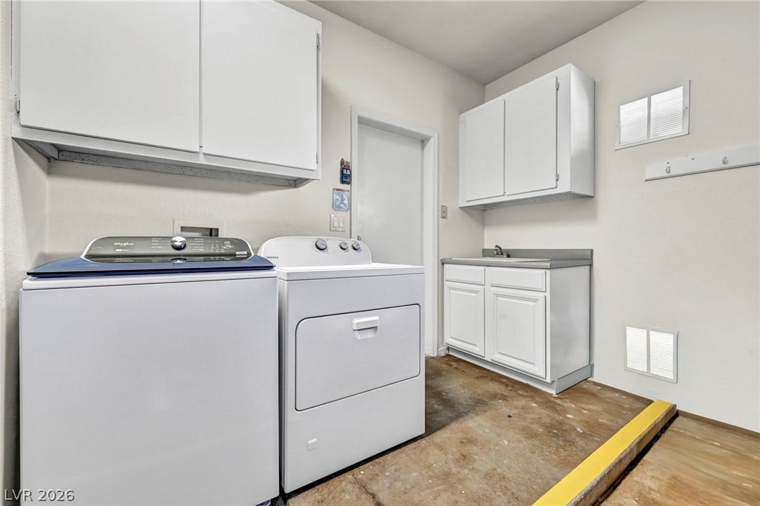 10020 Villa Ridge Drive, Las Vegas, NV 89134 A functional laundry area includes cabinetry and a convenient utility sink alongside concrete flooring.
