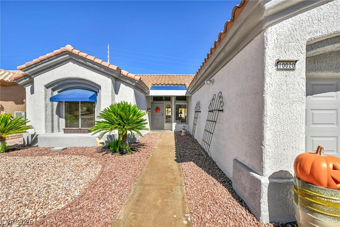 10020 Villa Ridge Drive, Las Vegas, NV 89134 A concrete walkway guides guests to the entryway of this stucco-finished home under clear blue skies.