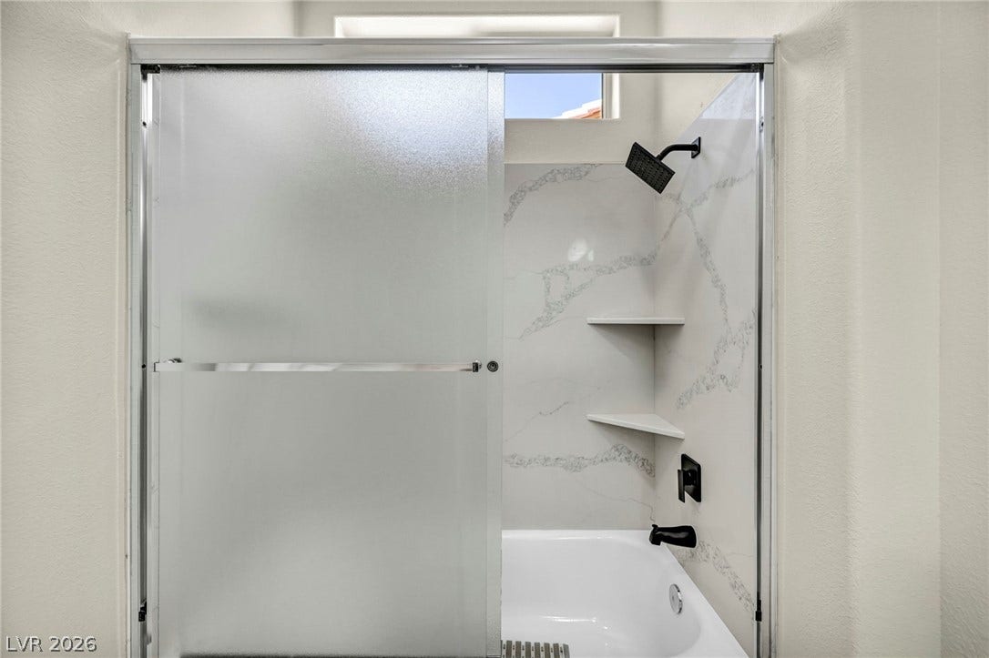 10020 Villa Ridge Drive, Las Vegas, NV 89134 A glass-enclosed tub and shower combination is accented by stone-patterned surround walls.