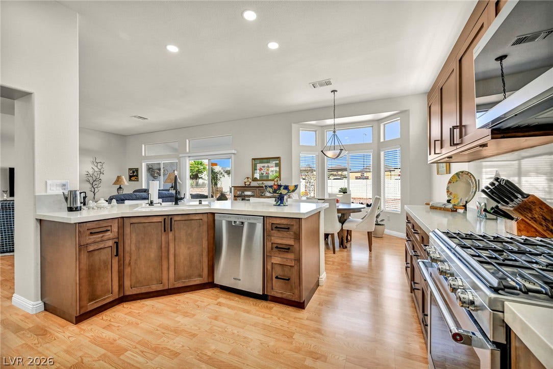 10020 Villa Ridge Drive, Las Vegas, NV 89134 Warm wood cabinetry and durable solid-surface countertops anchor this sunlit open-plan kitchen.