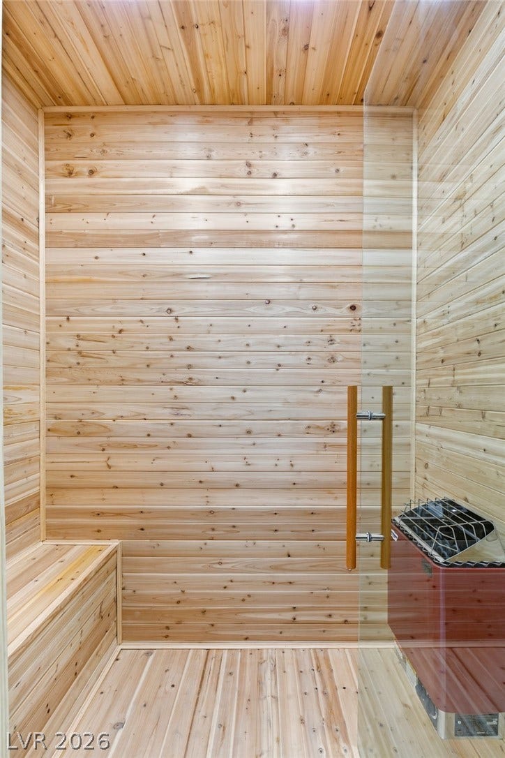 10626 San Vercelli Court, Las Vegas, NV 89141 Natural wood paneling wraps this private home sauna featuring a modern glass entry door.