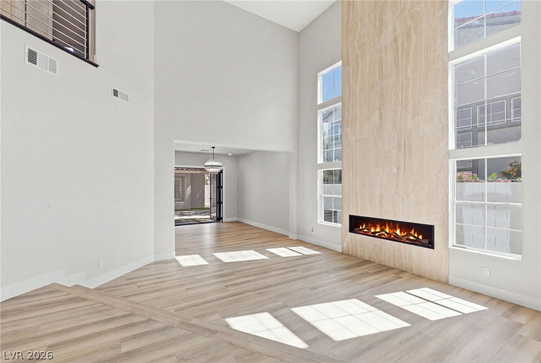 10626 San Vercelli Court, Las Vegas, NV 89141 Soaring ceilings and a floor-to-ceiling fireplace anchor this light-filled main living space.