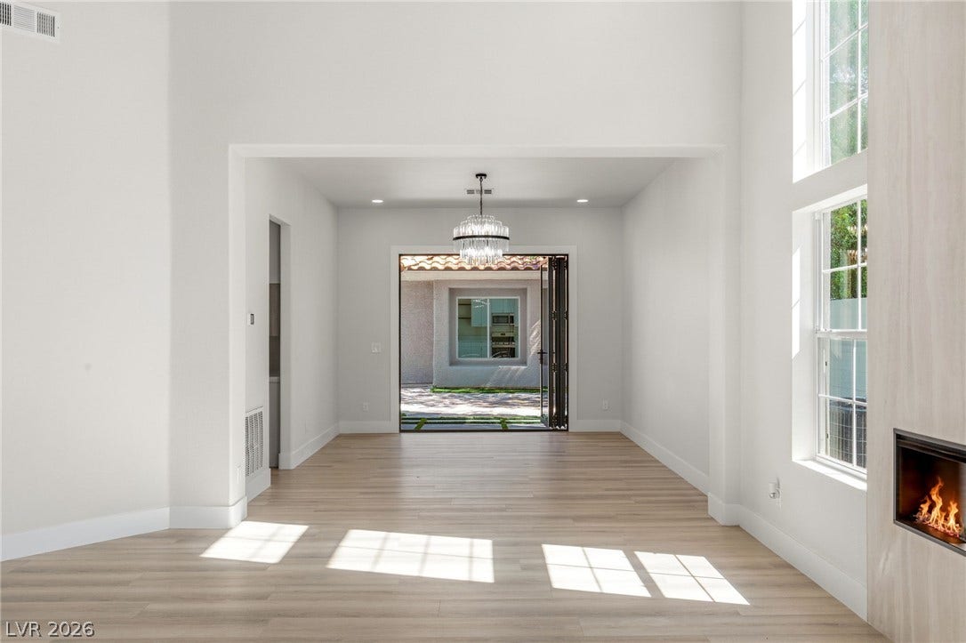 10626 San Vercelli Court, Las Vegas, NV 89141 Hardwood floors and soaring ceilings frame this open living space with a modern fireplace.