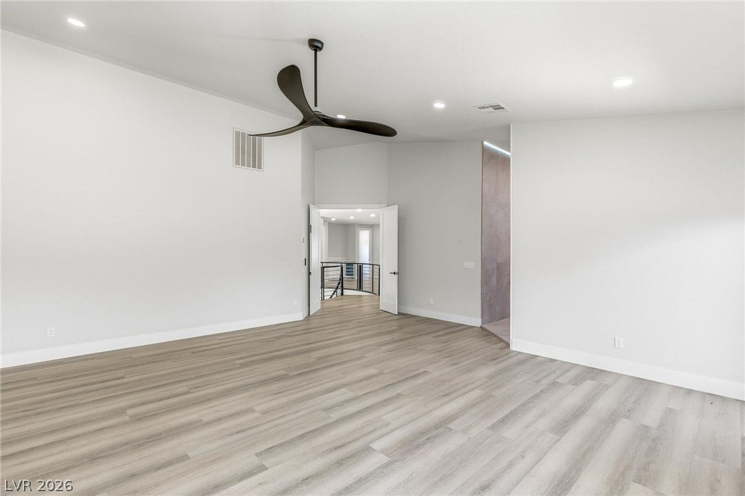 10626 San Vercelli Court, Las Vegas, NV 89141 A spacious bedroom features modern wood floors, high ceilings, and recessed lighting.