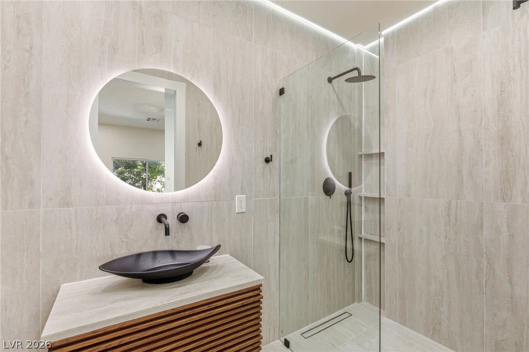 10626 San Vercelli Court, Las Vegas, NV 89141 Stone tiled walls and modern fixtures create a sleek, spa-like atmosphere in this bathroom.