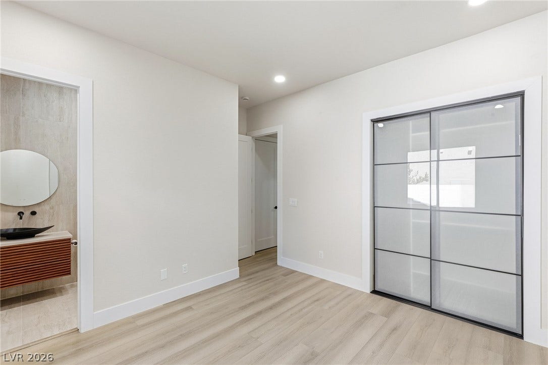 10626 San Vercelli Court, Las Vegas, NV 89141 Smooth wood floors and recessed lighting define this modern bedroom featuring a glass-front closet.