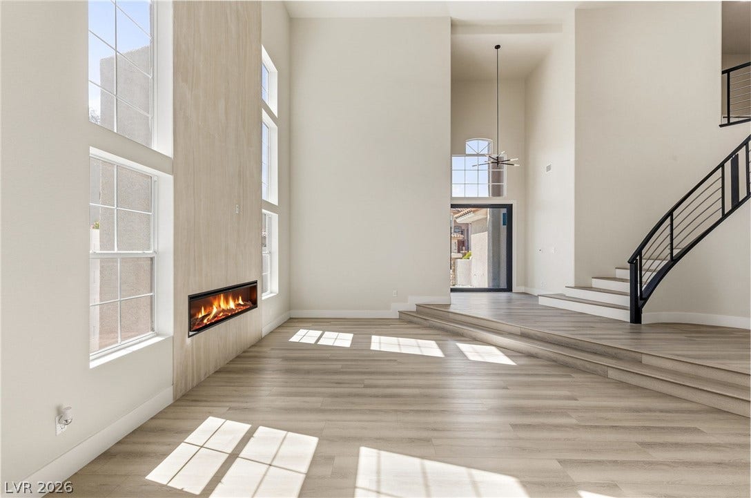 10626 San Vercelli Court, Las Vegas, NV 89141 Soaring ceilings, a modern inset fireplace, and wood-look flooring anchor this airy open space.