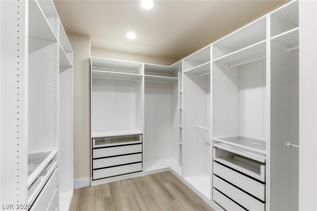 10626 San Vercelli Court, Las Vegas, NV 89141 Custom floor-to-ceiling built-ins and smooth flooring define this spacious walk-in closet.