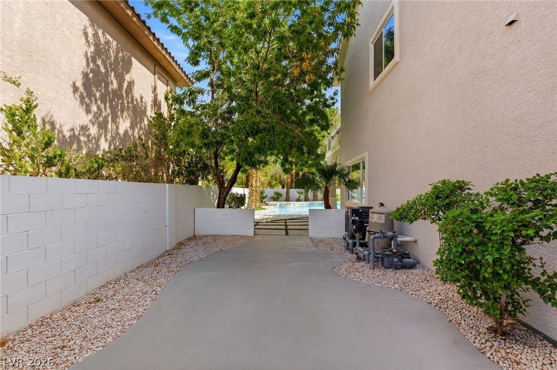 10626 San Vercelli Court, Las Vegas, NV 89141 A paved side pathway leads past stucco walls toward the backyard pool area.