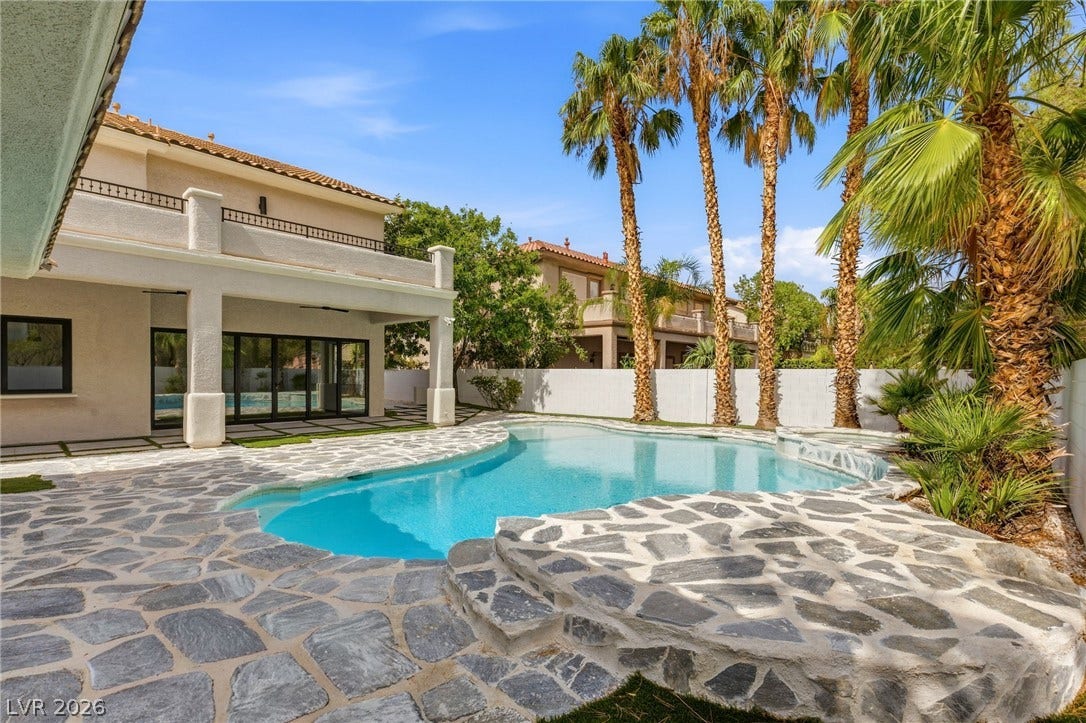 10626 San Vercelli Court, Las Vegas, NV 89141 An inviting backyard oasis features a flagstone patio surrounding a sparkling pool bordered by tall palms.