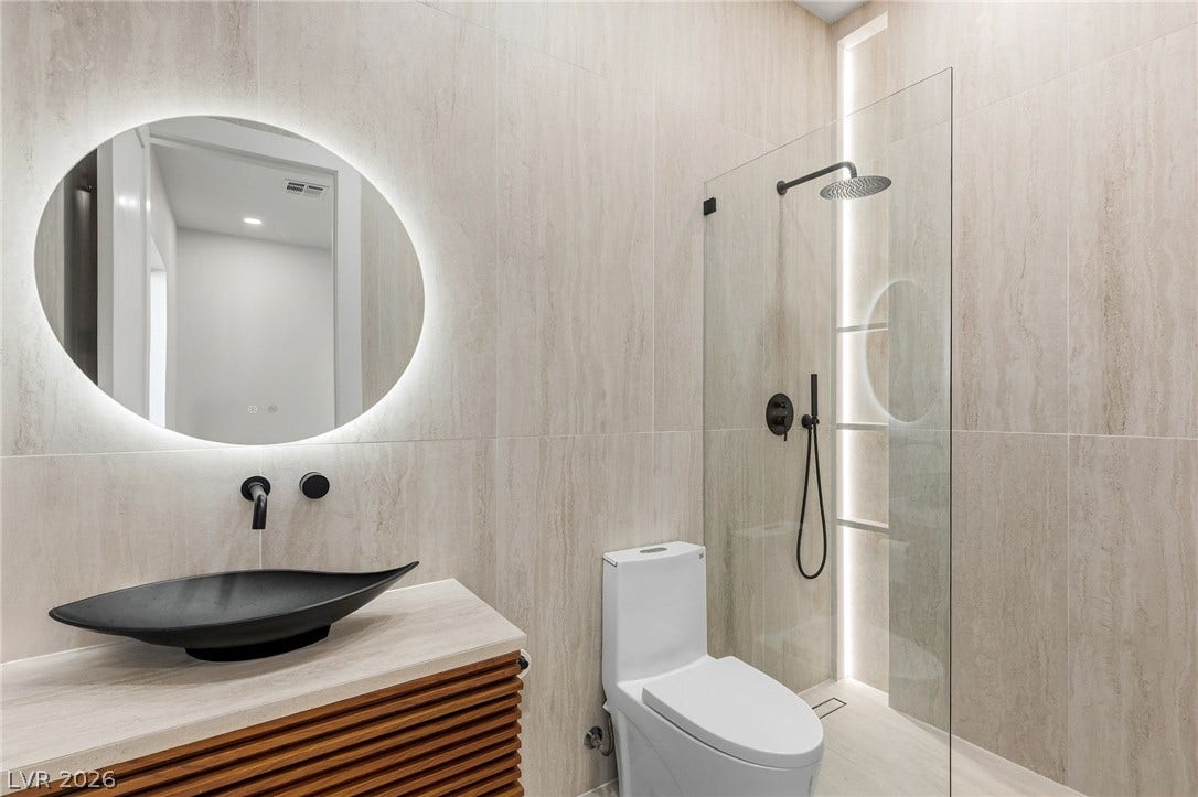 10626 San Vercelli Court, Las Vegas, NV 89141 Floor-to-ceiling tiling and a glass-enclosed shower define this modern, minimalist bath space.