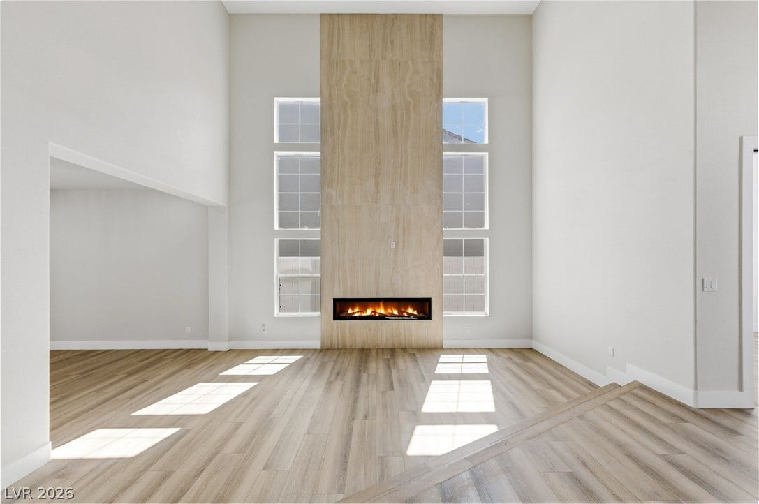 10626 San Vercelli Court, Las Vegas, NV 89141 Soaring ceilings and a floor-to-ceiling fireplace anchor this light-filled modern living space.