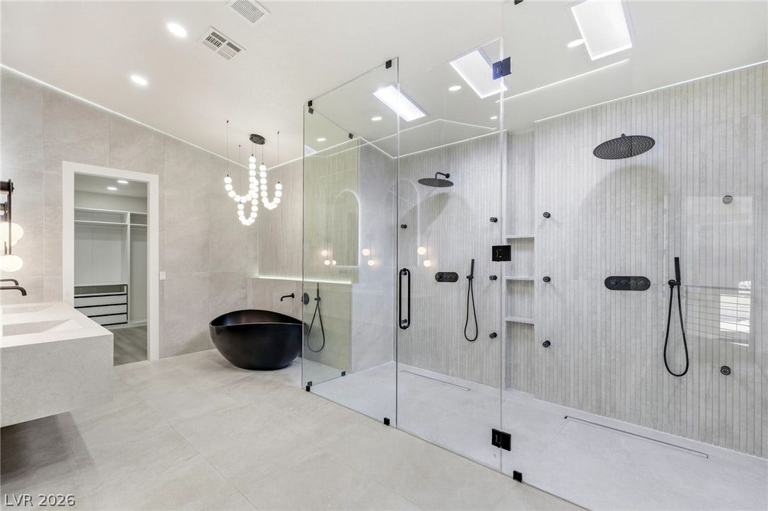 10626 San Vercelli Court, Las Vegas, NV 89141 Sleek modern finishes define this bathroom featuring a glass shower, soaking tub, and tiled floors.