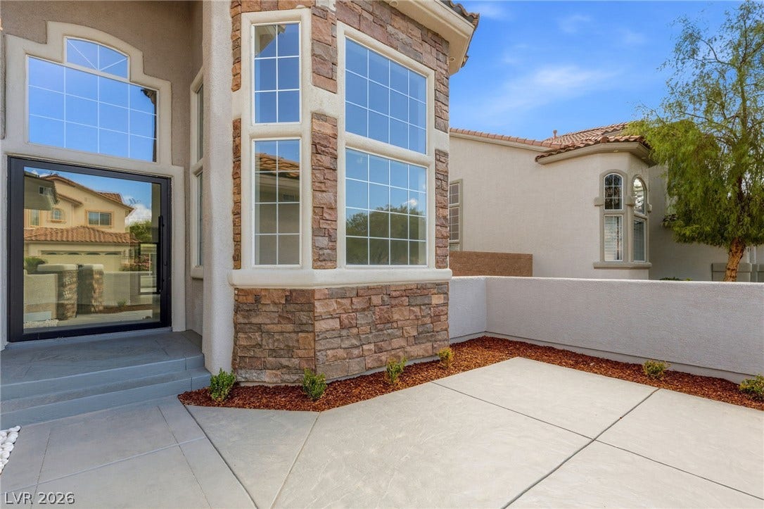 10626 San Vercelli Court, Las Vegas, NV 89141 A private front courtyard entry welcomes guests with classic stone accents and multi-pane windows.