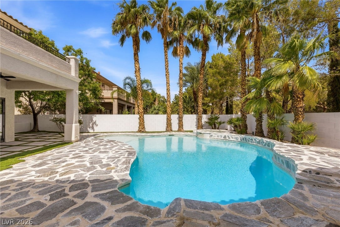 10626 San Vercelli Court, Las Vegas, NV 89141 Lush palm trees frame a sparkling pool surrounded by flagstone decking.