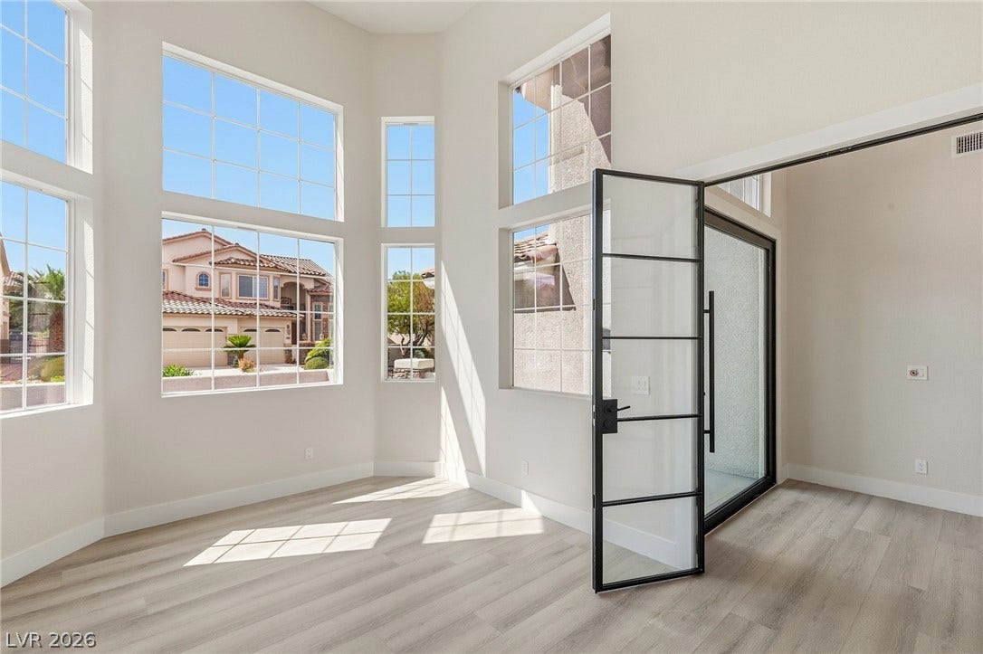 10626 San Vercelli Court, Las Vegas, NV 89141 Soaring ceilings and grid-style windows highlight this airy living space with light-toned floors.